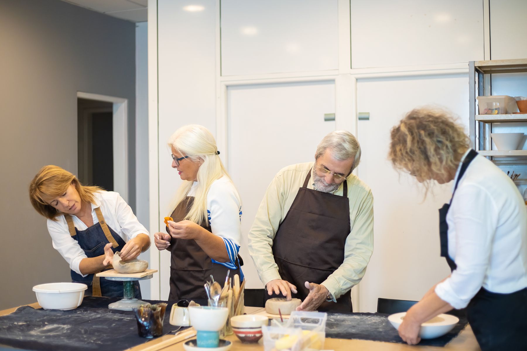 People shaping clay in a pottery workshop